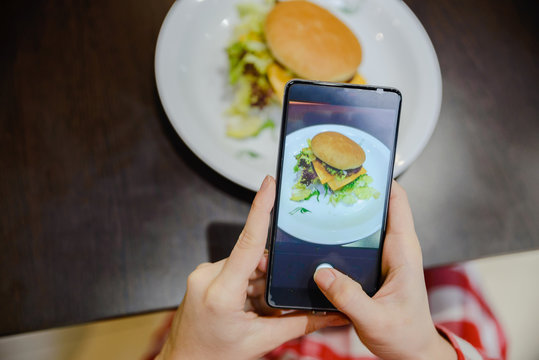 woman take picture of hamburger on her phone