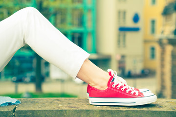Girl in sneakers lying on the bench