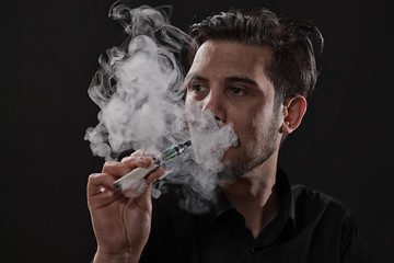 Portrait of man who is smoking electronic cigarette. 