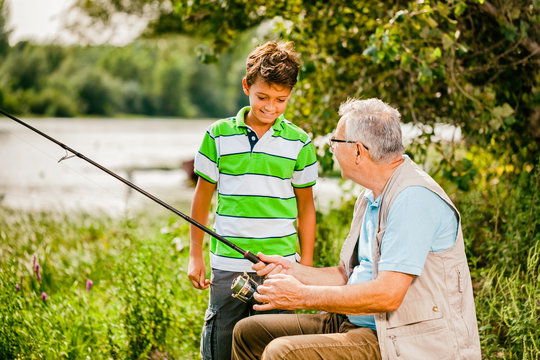 Grandfather and grandson are fishing on sunny day. 