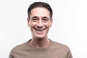 Lovable smile. The portrait of a pleasant middle-aged man posing for the camera and smiling while standing isolated on the white background