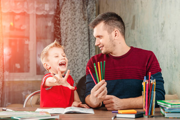 The father and his little son fool around doing homework for the school.