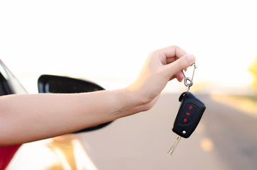 Women show the car keys outside the car window happily.