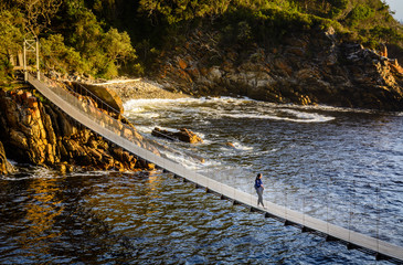 A girl is standing on the suspension bridge in Storms River Mouth national park in South Africa
