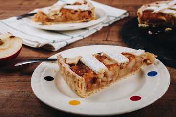 Apple tart slices on plates, wooden table