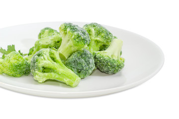 Frozen broccoli on dish closeup on a white background