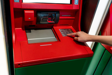 Hand of Asian woman pressing digit buttons on ATM machine.