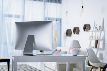 silver computer on table with lamp in room