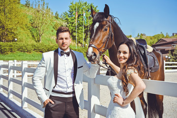 Beautiful newlyweds on a horses farm celebrating wedding in spring nature 
