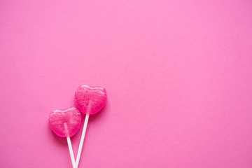 Couple of 2 heart shaped lollipops on pink. Valentine's day background, greeting card concept.