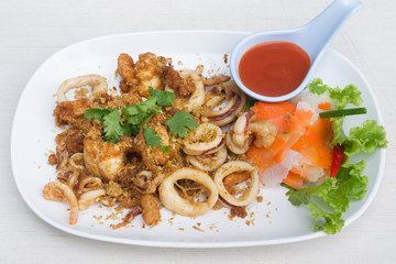 Fried squid with garlic in white dish on the table.