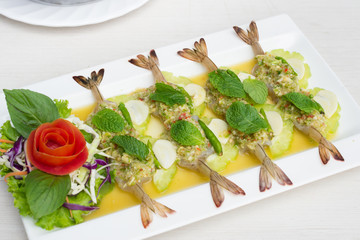 Shrimp in fish sauce with cabbage sliced in white dish on table.