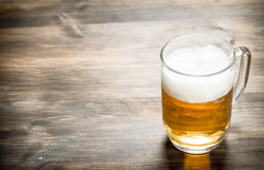 mug of fresh beer. On wooden table.