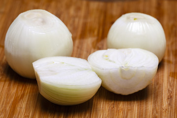 Onion and onion slices on wooden cutting board.