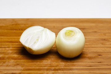 Onion and onion slices on wooden cutting board.