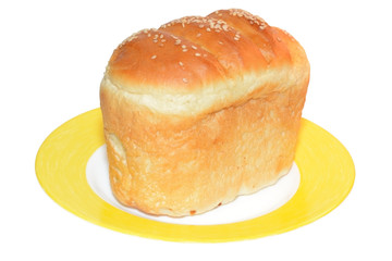 A loaf of white bread with sesame seeds on yellow plate isolated on white background