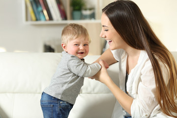 Mother helping to stand to her son who looks at you