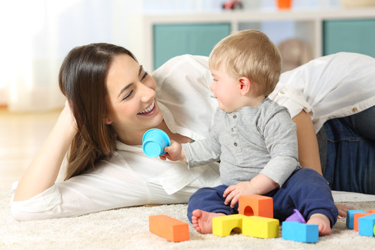 Joyful mother and baby playing on a carpet