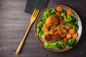 Chicken steak in breadcrumbs with vegetables on a plate. Menu, restaurant concept. Served in. Top view. Copyspace