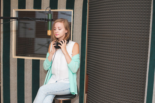 Young woman prepares for recording a song in a professional music studio
