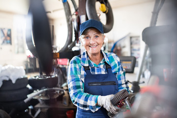 Fototapeta na wymiar Senior female mechanic repairing a car in a garage.