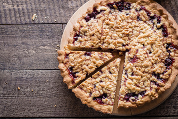 Homemade tasty shortcrust raspberry pie with crumble on old wooden table background. Top view, copy space