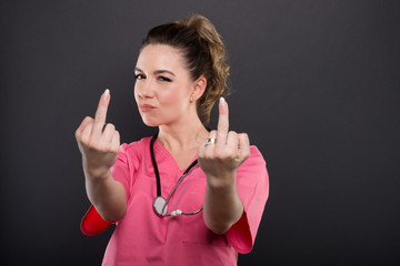 Portrait of attractive lady doctor showing double obscene gesture
