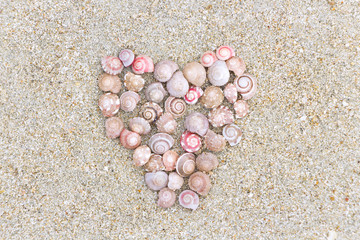 A symbol of love made a Heart shape of the shell on the beach near the sea.