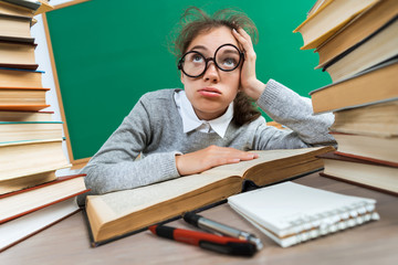 Exhausted or bored young student around a lots of books. Photo of student in classroom, education concept