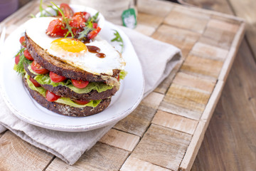 Toast from a grain bread with cheese and tomatoes and egg. Vegetarian food. on a white plate and a wooden background. Useful breakfast. Free space for writing text.