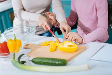 Cooking with inspiration. Loving caring devoted mother chopping vegetable and making a salad and teacher her daughter to chop