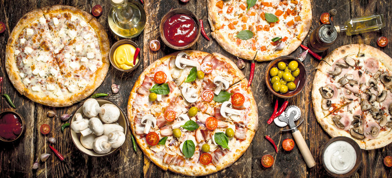 variety of pizzas. On wooden background