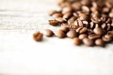 Coffee beans on light wooden background with copyspace for text. Coffee background, food frame, texture concept. Banner