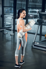 Fototapeta na wymiar young fit woman with rolled yoga mat at gym