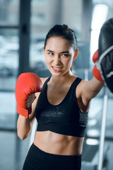 expressive young female boxer training at gym