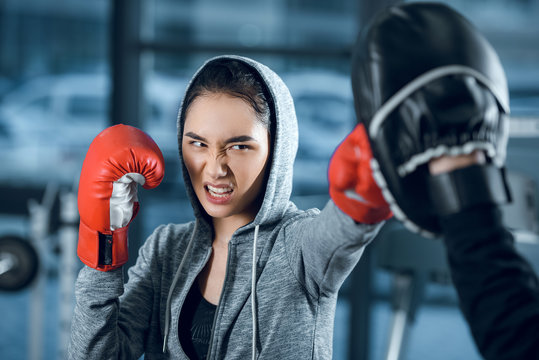 agressive young female boxer training at gym