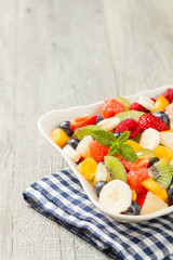 Delicious fruit salad with fresh fruit. Wooden, gray table in the background.