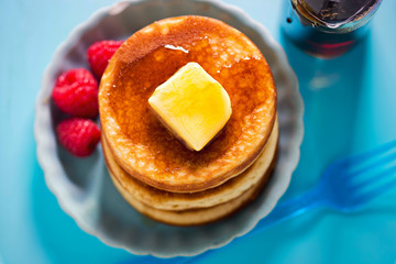 American pancakes with butter, maple syrup and raspberries 