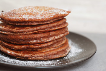 Chocolate Homemade Pancakes with Sugar Powder in Black Plate. Breakfast for Children.