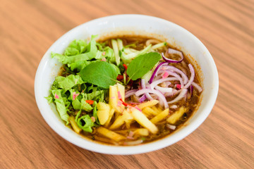 Laksa on wooden table. Laksa is a spicy noodle soup popular in the Peranakan cuisine.