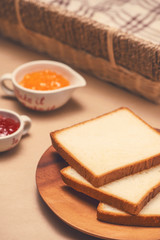 Toast with strawberry and orange jam on a plate on table.