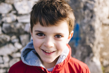 portrait of 9 year old boy with red jacket outside