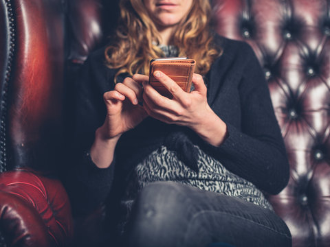 Woman on leather sofa using phone