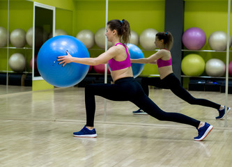 Young model girl makes exercises at the gym in front of mirror