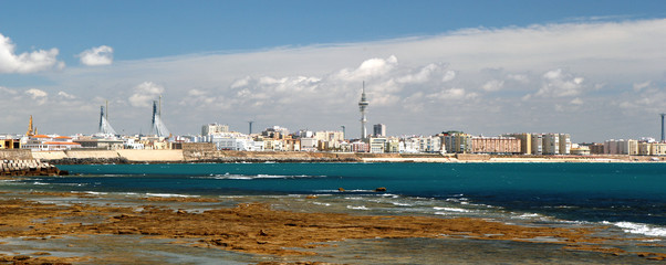 Obraz premium Rocky oceanic coastline and downtown on background