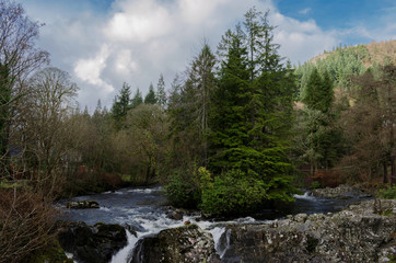 Beautiful river scene with trees on a small island and a waterfall in the foreground at the village of Betws Y Coed in North Wales