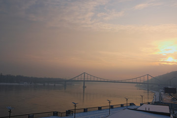 Amazing view on the Dnipro River and Footbridge. Winter sunrise on foggy morning. Kyiv, Ukraine