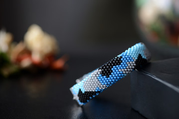 Blue beaded bracelet camouflage coloring on a dark background close up