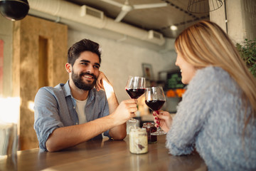 Beautiful couple drinking red wine at cafe and having romantic moments. Couple celebrating anniversary or Valentin's day.