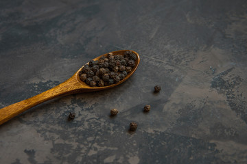 Black pepper on a wooden spoon, copy space